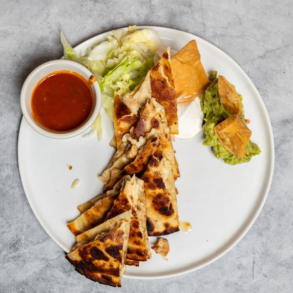 Golden-brown quesadilla triangles with melted cheese, served with salsa, guacamole, sour cream, and lettuce.